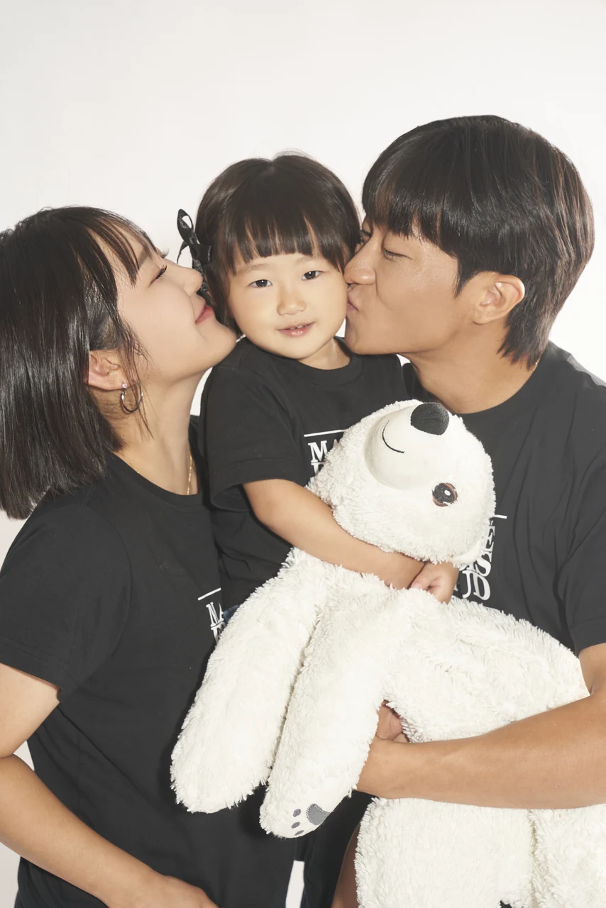 양쪽에서 아이에게 입맞추는 부모의 가족사진